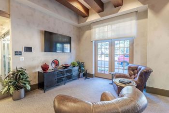 A living room with a brown leather chair and a flat screen tv mounted on the wall